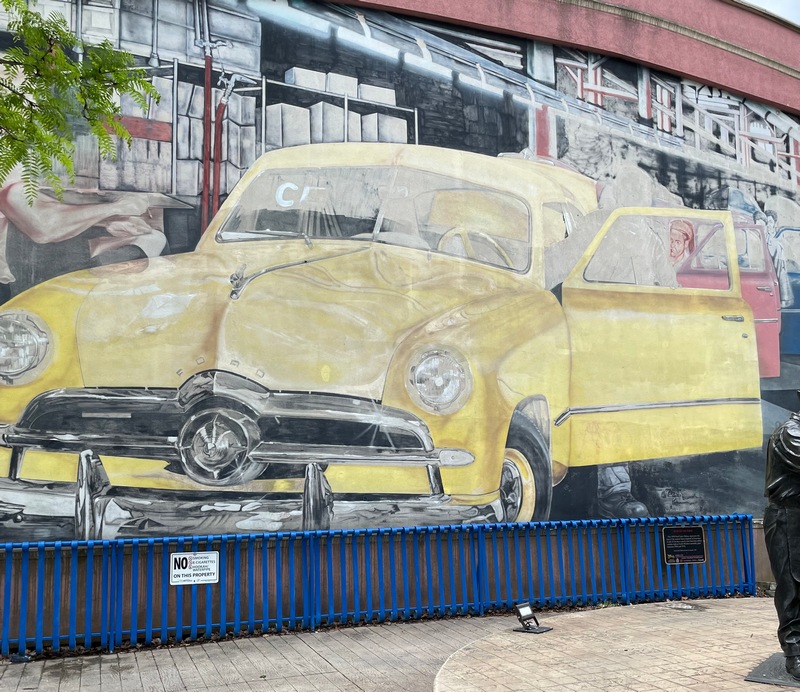 Mural in Windsor Ontario called "End of the Line." Ford workers conducting final checks on a yellow, red and blue Ford Tudor Deluxe at the end of production